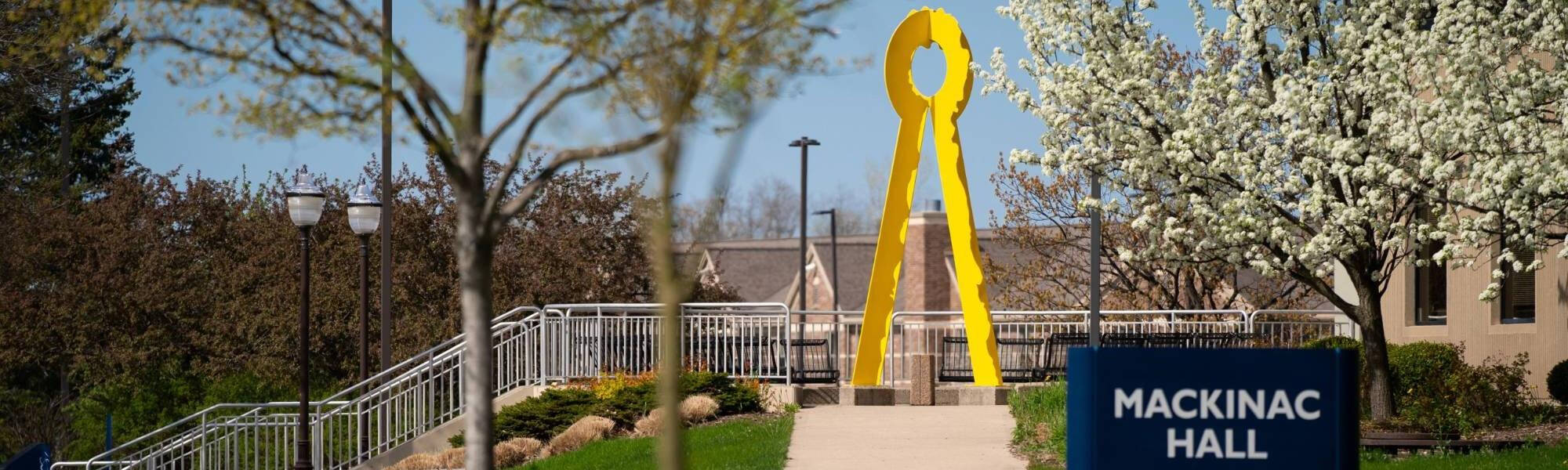 Yellow Art Sculpture behind a sign labeled "Mackinac Hall"
